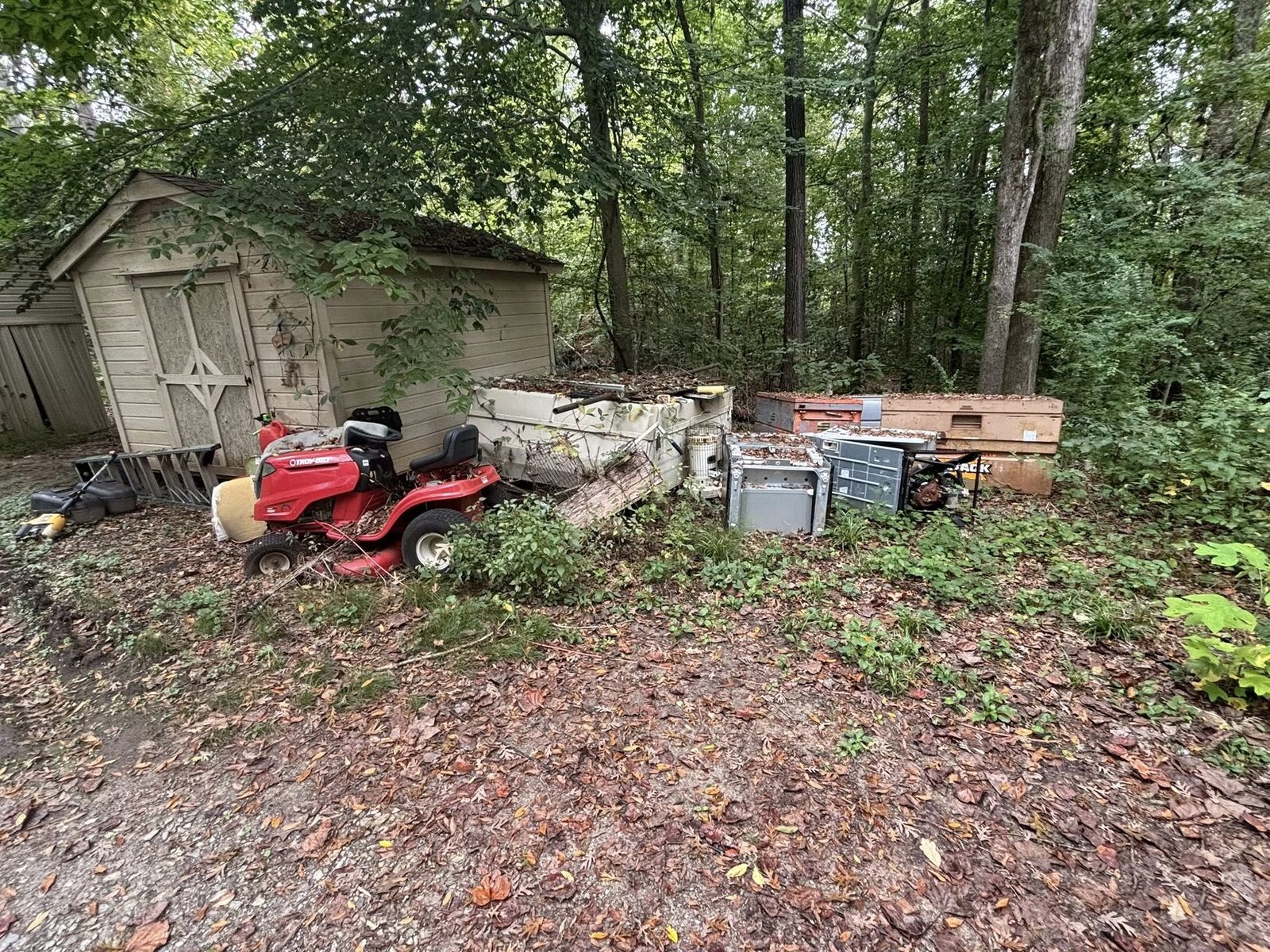 Yard full of appliances, mower, and debris