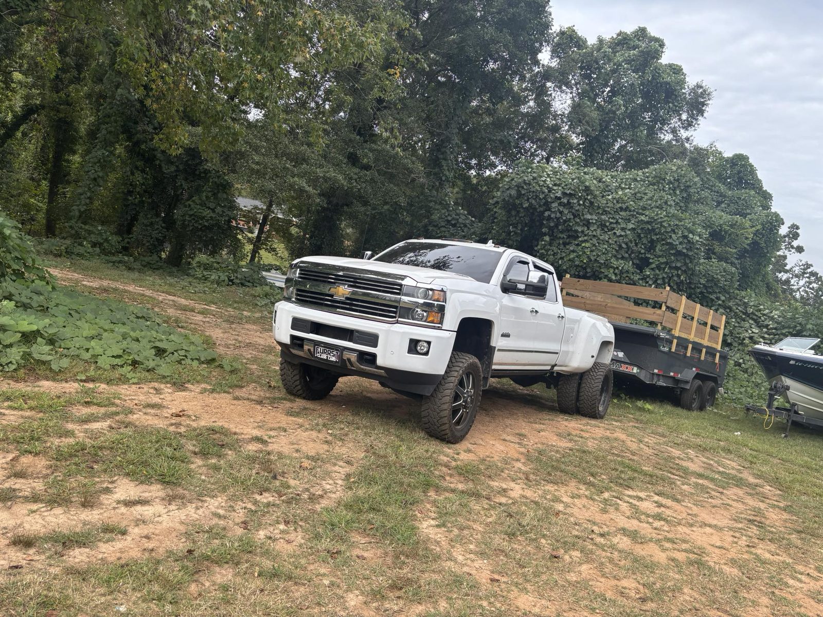 White Chevy truck towing dump trailer at job site